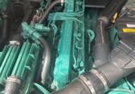 Close-up of a green Volvo Penta marine diesel engine with hoses and clamps visible in the engine bay.