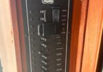 Close-up of a black electrical control panel with multiple labeled switches on a wood cabinet door, likely boat or RV circuitry