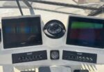 Boat helm dashboard with two Garmin displays, a central compass, and multiple switch panels below.