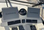 Boat helm with two Garmin displays, a compass, and control panels on a beige dashboard.