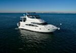 White motor yacht cruising on calm blue ocean under a clear sky.