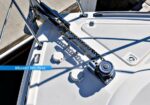 Close-up of a boat windlass and anchor chain on a sunlit deck, with 'Maxwell Windlass' branding visible.