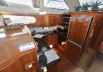 Wood-paneled boat galley with refrigerator, oven, microwave, and black countertop; potted plants on top.
