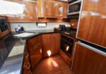 Wooden galley kitchen on a boat with black countertops, sink, and built-in oven.