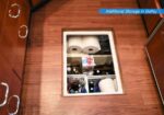 Open storage compartment in a galley with paper towels, bottles, and miscellaneous supplies.