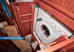 Washer-dryer combo installed in a wooden cabinet with doors open showing front-loading unit.