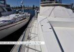 White motor yacht at a marina with wide side decks and railings for easy passage to the bow.