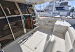 Yacht deck with glass doors, a stainless ladder, and built-in seating overlooking the marina.