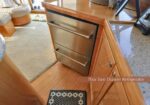 Built-in Thor two-drawer stainless steel refrigerator inside a wood kitchen cabinet, with the cabinet door open.