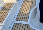 White sailboat cockpit with teak-style non-slip deck planks and built-in seating areas on either side.