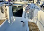 Sailing boat cockpit with coiled ropes hanging from lines, a closed cabin hatch, and teak deck panels.