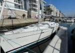 White motor yacht docked at a marina with modern apartment buildings along the waterway