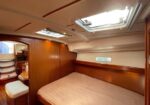 Wood-paneled boat cabin with a double bed, built‑in wardrobe, and skylights overhead.