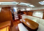 Luxurious yacht cabin with an oval wood dining table, white cushioned seating, and polished wood cabinets.