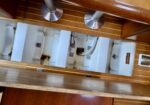 Under-sink area showing white pipes, rust stains, and metal brackets between wooden cabinet panels.