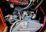 Yanmar marine diesel engine mounted in a boat’s engine compartment with red battery cables and various hoses visible.
