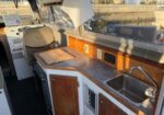 Boat galley with wood cabinetry, stainless sink, and counter space near the helm area.