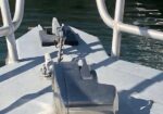 Close-up of anchor windlass and chain on the bow of a boat, with railing and water in the background.