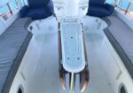 Cockpit of a white yacht with U-shaped gray cushioned seats along the sides and a center folding table.