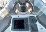 Boat helm with steering wheel and navigation panel featuring a large touchscreen display and analog gauges.