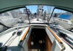 View from inside a sailboat cockpit looking toward a marina, with deck, lines, and other boats surrounding the stern hatch