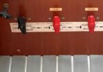 Close-up of a brown control panel with three levers: a black switch on the left and two red switches labeled START and HOUSE, with ON/OFF labels nearby.