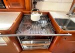 Kettle on a gas stove in a compact wooden galley kitchen. A sink sits to the right.