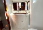 Compact boat head with white vanity, chrome faucet, and mirrored cabinet above; wooden trim and doorway nearby.