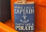 Blue metal flask with white lettering reading, 'Work like a Captain, Party like a Pirate,' and an anchor graphic in the center.