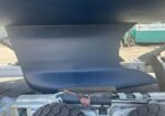Underbelly of a large blue boat hull resting on a trailer in a boatyard, with supports beneath the keel.