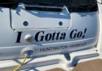 White boat stern with the slogan 'I Gotta Go!' in dark blue letters, Huntington Harbour, and a yellow power cord plugged into an outlet.