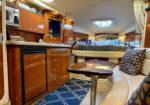 Luxurious yacht interior with a wood-paneled galley, curved seating, and a small table in the foreground.