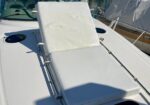 White cushioned sun lounger on the deck of a boat, with a padded backrest and metal railing, docked at a marina.