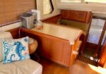 Cozy boat interior with a beige counter, wooden cabinets, and a small kitchen area next to a cream sofa with a blue seahorse cushion.