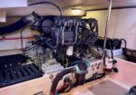 Diesel boat engine in a cramped engine room with hoses, filters, and wiring visible around the unit