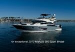 Luxurious white motor yacht on calm blue harbor water; a 2013 Marquis 500 Sport Bridge yacht.