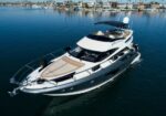 Luxury white motor yacht in a calm marina, with waterfront homes visible in the background.