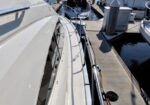 Close-up of a white yacht at a marina dock, with railing and gangway visible along the deck.