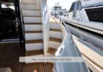 Yacht stairs with teak treads leading from deck to the bridge, docked at a marina.