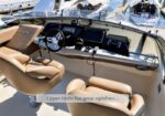 Cockpit of a luxury motorboat with tan captain and passenger seats, steering wheel, and navigation displays; marina in the background. A caption on the image reads 'Upper Helm has great sightlines...'