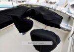 Cockpit of a boat with black protective covers on seating and controls; a label reads Full set of covers... .