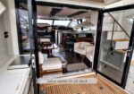 Luxurious yacht salon with glass doors open to the aft deck, beige seating, and wooden flooring.