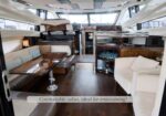 Luxurious boat salon with cream sofas, wood tables, and a front seating area for entertaining guests, view from the cabin doorway.