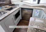 Modern galley kitchen with granite countertops, stainless steel appliances, and a window above the counter.