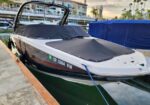Powerboat docked at a marina with a covered cockpit and blue mooring lines securing it to the dock.