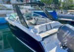 White and navy Yamaha speedboat docked in a marina, open cockpit with white seating and a blue canopy/tower.