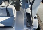 White and gray boat cockpit seating with a central step down and a black-armrest leaning post on the right side