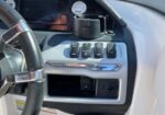 Dashboard of a vehicle showing row of toggle switches, cup holder, and open storage pocket near the steering wheel.