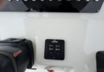 Close-up of a black Lenco control switch on a white boat hull, showing up and down arrows.