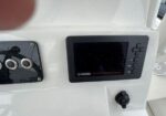 Yamaha multifunction display mounted on a white boat console next to a panel with circular ports and a black knob below.